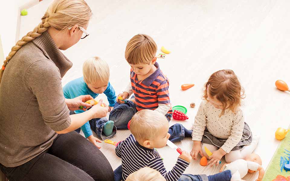 Photo d'illustration présentant une assistante maternelle et 4 enfants